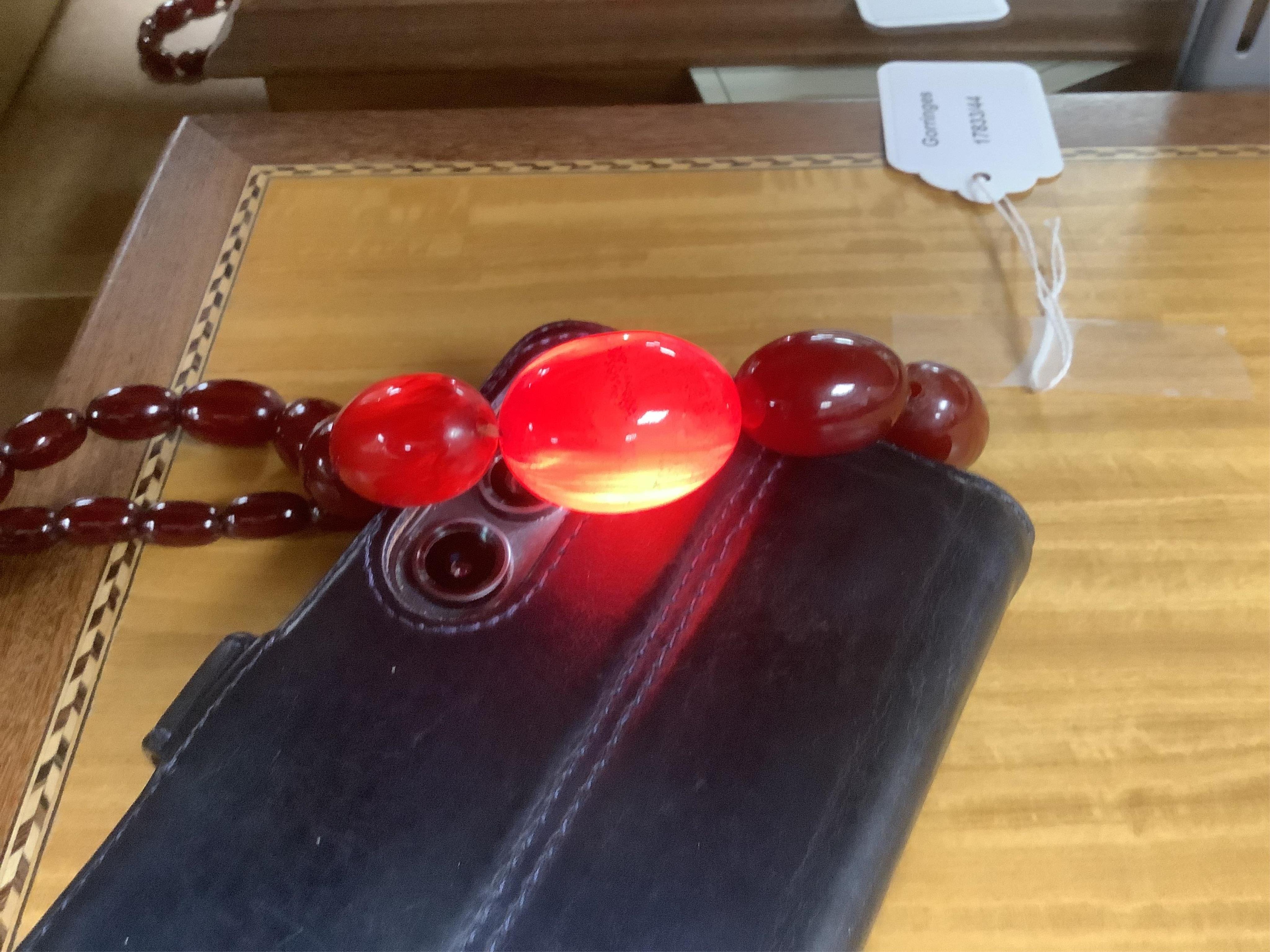 A single strand graduated oval simulated amber bead necklace, 72cm, gross weight 64 grams, together with a simulated cherry amber bracelet.